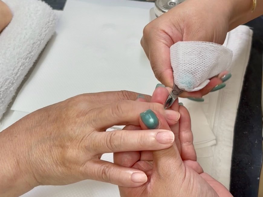 ニッパーで爪まわりの甘皮を整えている手元